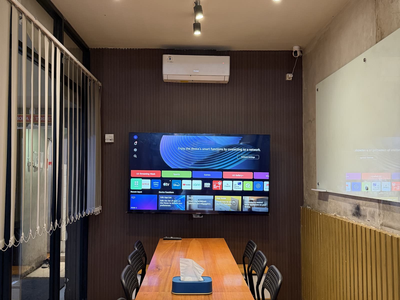 VIP room Warkop Bulungan Blok M: meja panjang, TV, whiteboard, dan AC